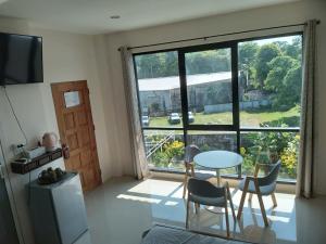 a room with a table and chairs and a large window at ขุนโลหะ K̄hun loh̄a in Phuket