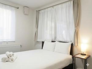a bedroom with a white bed and a window at The MOON in Sapporo