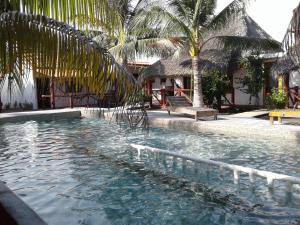 a swimming pool next to a resort with palm trees at Bungalows Familiares in Monterrico