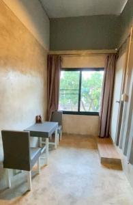 a living room with a table and a window at innbox Chiangmai Hotel in Ban Si Ngam
