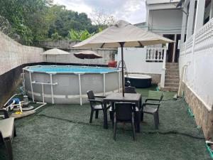 a table and chairs with an umbrella next to a swimming pool at Hotel Buganvilla in Guaduas