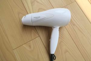 a white hair dryer sitting on top of a wooden table at 宇都宮ゲストハウス花ニ嵐 Guesthouse Hana ni Arashi in Utsunomiya