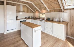 a kitchen with white cabinets and a wooden ceiling at Beautiful Home In Ans By in Roe