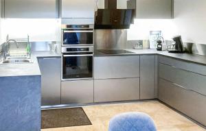 a kitchen with stainless steel appliances and a blue chair at 3 Bedroom Amazing Home In Mutigney in Mutigney