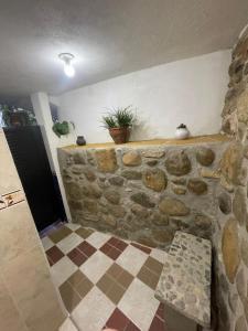a room with a stone wall with a bench and a plant at Ecohotel Naranjos in Jenesano