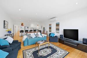 a living room with a blue couch and a tv at Tide & Town - Perfectly Located! in Inverloch