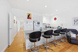 a kitchen with a counter and four bar stools at Tide & Town - Perfectly Located! in Inverloch