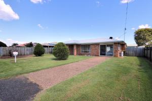 a brick house with a fence in a yard at 13 Natalie Street Bargara in Bargara