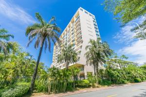 a tall white building with palm trees in front of a street at Yumian Cloud Seaview Hotel in Sanya