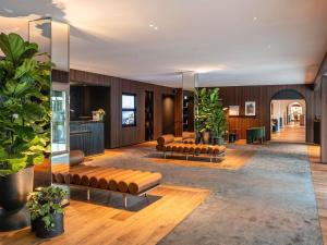 ein Wohnzimmer mit Ledersofas und Pflanzen in der Unterkunft Novotel Luxembourg Kirchberg in Luxemburg (Stadt)