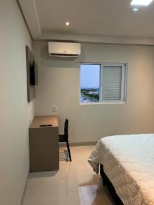 a bedroom with a bed and a desk and a window at Hotel Blox Sorriso in Sorriso