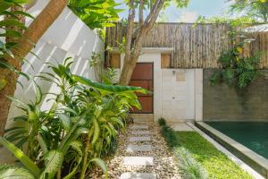 a garden with a walkway leading to a garage at Du Ciel Villa by Betterplace in Canggu