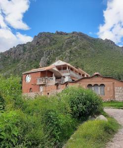 a building with a clock on the side of a mountain at Sumaq Illary Bonito Amanecer in Urubamba