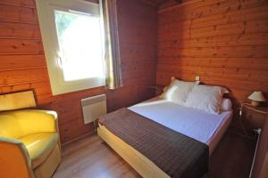 a bedroom with a bed and a window and a chair at Gîte 87G5511 in Sussac