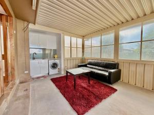 a living room with a black leather couch and a red rug at 72 Cobra Street House in Dubbo