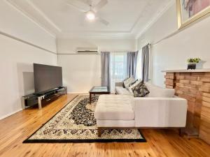 a living room with a white couch and a flat screen tv at 72 Cobra Street House in Dubbo