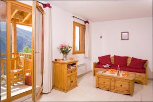 a living room with a couch and a balcony at Madame Vacances Les Balcons Des Airelles in Les Orres