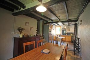a dining room with a wooden table and a kitchen at Les pierres du mas in La Porcherie