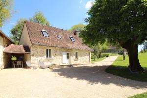 a stone house with two chairs and a tree at Cirèges in Le Chalard