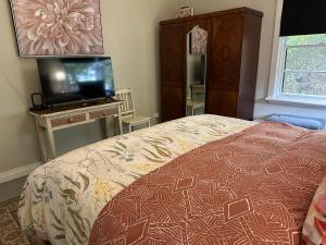 a bedroom with a bed and a flat screen tv at Bush Retreat Farm Stay 1BR Guest Suite in Alberton West