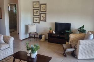 a living room with a couch and a tv at Fynbos & Foam in Herolds Bay