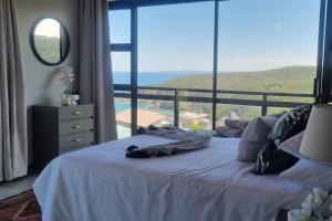 a bedroom with a white bed with a large window at Fynbos & Foam in Herolds Bay