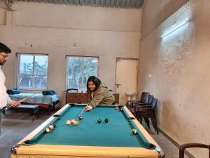 a woman playing a game of pool in a room at Rajlok Resort in Mulshi