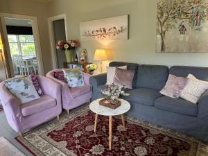 a living room with two purple couches and a table at Bush Retreat Farm Stay 1BR Guest Suite in Alberton West