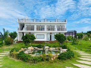 a white house with a pond in front of it at ThmorDa Resort in Koh Rong Sanloem