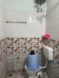 a bathroom with a toilet with a blue bucket on it at Teja Residency in Alāndurai