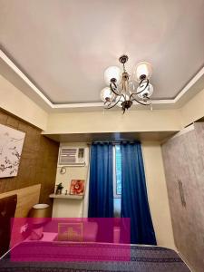 a bedroom with a purple bed and a chandelier at Janeeka's Airie Avida Riala Cebu in Cebu City
