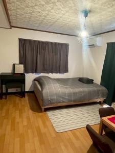 a bedroom with a bed and a window and a table at HOSTEL KURIYA OSAKA in Izumi-Sano