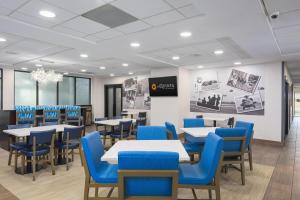 a dining room with tables and blue chairs at La Quinta by Wyndham Clarksville in Clarksville