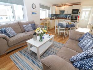 a living room with a couch and a table with flowers at Atlantic Waves in Carbis Bay