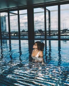 a woman is swimming in a swimming pool at Andaz Munich Schwabinger Tor, By Hyatt in Munich