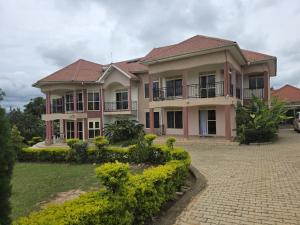 a large pink house with a brick driveway at Cafe La Vida in Mbarara