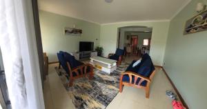 a living room with blue chairs and a television at Cafe La Vida in Mbarara