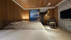 ein Hotelzimmer mit zwei Betten und einem Flachbildfernseher in der Unterkunft GOGO Hotel City Hall in Taichung