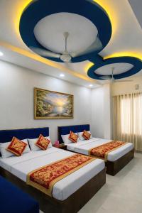 two beds in a room with a blue and yellow ceiling at Hotel Tirupati Heights Ujjain # Near Railway Station # Top Rated Property in Ujjain