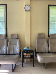 a waiting room with two chairs and a clock on the wall at Roy Lao House in Khao Lak