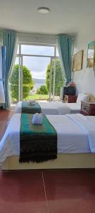 a bedroom with two beds and a large window at ThmorDa Resort in Koh Rong Sanloem