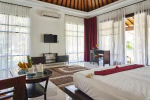 a bedroom with a large bed and a table with a desk at Rossa Garden Hotel Boutique in Candidasa +66 photos