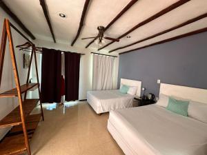 a bedroom with two beds and a ceiling fan at Lodge Arenas Costa Maya in Mahahual