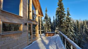 a wooden house with a balcony in the snow at Le Val d'Isère - Les Chalets Spa Canada in La Malbaie