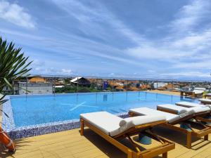 a large swimming pool with lounge chairs on a roof at XO Canggu adults only in Canggu