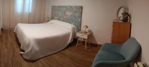 a bedroom with a white bed and a blue chair at Mi Huella in Tomelloso
