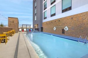 a swimming pool with tables and chairs next to a building at Home2 Suites By Hilton Calera in Calera