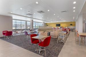 a waiting room with tables and chairs and windows at Home2 Suites By Hilton Calera in Calera