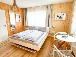 a bedroom with a bed and a table and a window at Hacienda Rooms - moderne Zimmer in ruhiger Lage - Room only ! in Friedrichshafen