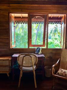 a table and chairs in a room with windows at Secret Beach Beachfront Villa in Papak